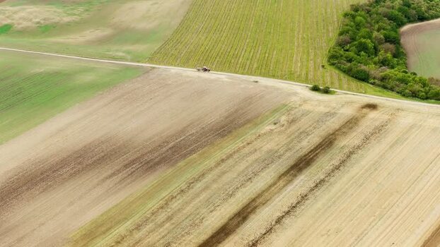 Aerial view of rolling agricultural fields and a tractor Czechia.