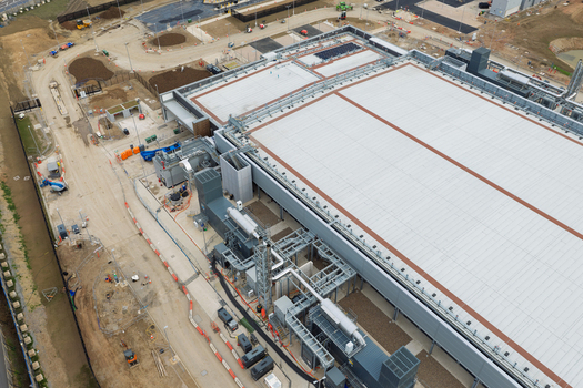 Aerial view of a data center facility with industrial cooling equipment rooftop ventilation systems and surrounding construction site United Kingdom.