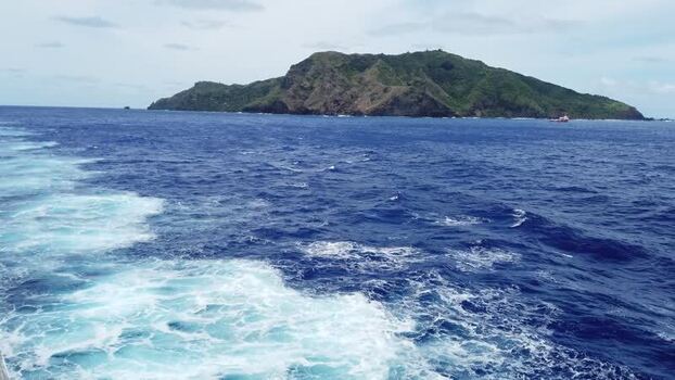 View of Pitcairn Island with a small boat Pitcairn Islands.