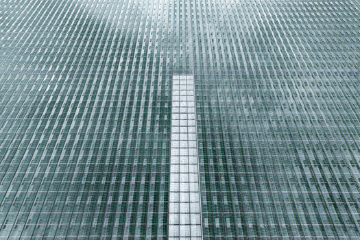 Aerial view of a large greenhouse farm with repeating glass panels and a central walkway in Poland. Aerial view of a large greenhouse farm with repeating glass panels and a central walkway in Poland.