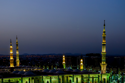 View of the illuminated minarets and domes of Al Masjid e Nabawi at night in Madinah Al Madinah Province Saudi Arabia.