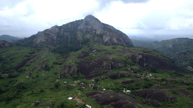 Aerial view of Idanre Hill featuring massive granite rock formations lush green vegetation and small traditional dwellings nestled in the landscape of Idanre Ondo State Nigeria. Aerial view of Idanre Hill featuring massive granite rock formations lush green vegetation and small traditional dwellings nestled in the landscape of Idanre Ondo State Nigeria.