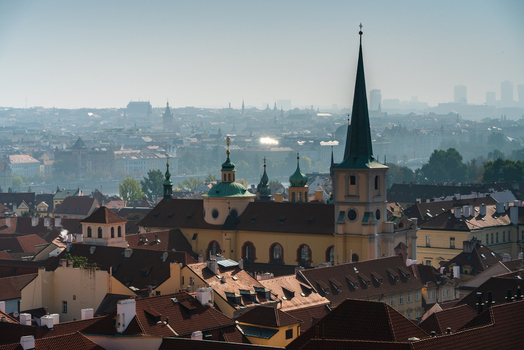 View of the Church of Saint Giles with its distinctive green spire and dome surrounded by historic red tiled rooftops in the old town of Prague Prague Czechia.