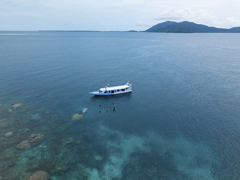 Aerial view of a boat floating on the turquoise waters of the Java Sea with snorkelers exploring the vibrant coral reefs Karimunjawa Central Java Indonesia.