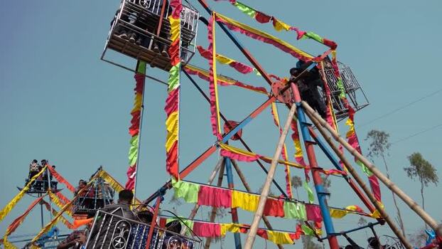 View of a traditional Ferris wheel with people in Bogura Bangladesh. View of a traditional Ferris wheel with people in Bogura Bangladesh.