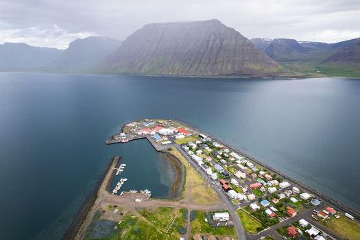 Aerial view of the coastal village of Flateyri on a narrow peninsula featuring a small harbor and colorful houses under a cloudy sky Flateyri Isafjardarbaer Iceland.