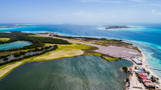 Aerial view of Los Roques archipelago featuring the airstrip turquoise Caribbean waters lush mangroves and coastal buildings in Los Roques Dependencias Federales Venezuela. Aerial view of Los Roques archipelago featuring the airstrip turquoise Caribbean waters lush mangroves and coastal buildings in Los Roques Dependencias Federales Venezuela.
