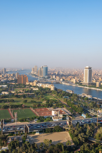 View of Nile river snaking through a vibrant cityscape modern buildings standing tall against the skyline lush greenery and busy roads below Zamalek Cairo Governorate Egypt. View of Nile river snaking through a vibrant cityscape modern buildings standing tall against the skyline lush greenery and busy roads below Zamalek Cairo Governorate Egypt.