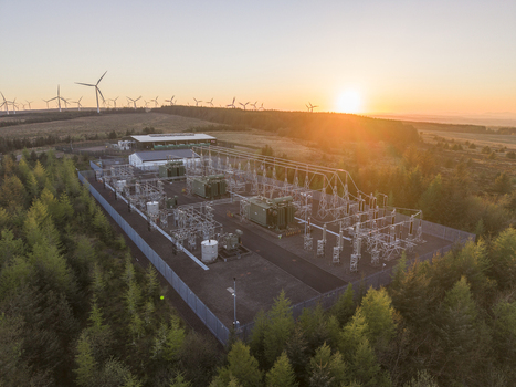 Aerial view of an electrical substation and wind turbines on Eaglesham moor during a golden sunset Kilmarnock Scotland United Kingdom.