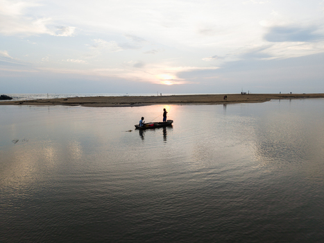 Aerial view of fishermen in a small boat on calm water near a sandy beach at sunset Galle Southern Province Sri Lanka. Aerial view of fishermen in a small boat on calm water near a sandy beach at sunset Galle Southern Province Sri Lanka.