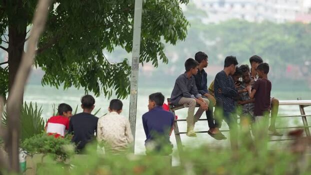 View of a group of young men sitting by the water in Dhaka Bangladesh.