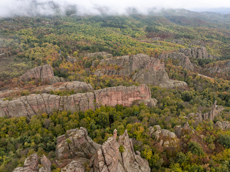 Aerial view of the Belogradchik Rocks featuring unique red sandstone formations surrounded by lush autumn forest in Belogradchik Vidin Bulgaria. Aerial view of the Belogradchik Rocks featuring unique red sandstone formations surrounded by lush autumn forest in Belogradchik Vidin Bulgaria.