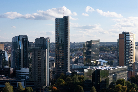 Aerial view of modern skyscrapers in the business district of Vilnius with glass facades reflecting the sky and surrounding green trees in Vilnius Vilnius County Lithuania.