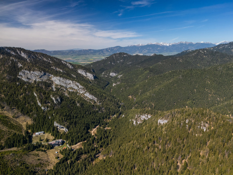 Aerial view of the lush Demanovska Dolina valley featuring dense pine forests rugged limestone cliffs and distant snow capped mountain peaks in Demanovska Dolina Zilina Region Slovakia. Aerial view of the lush Demanovska Dolina valley featuring dense pine forests rugged limestone cliffs and distant snow capped mountain peaks in Demanovska Dolina Zilina Region Slovakia.