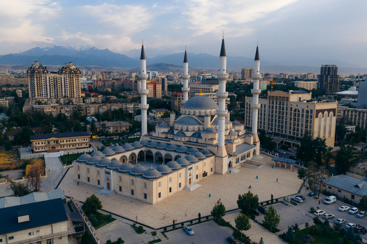 Aerial view of the Bishkek Central Mosque with its four minarets and large dome against the urban skyline and distant mountains in Bishkek Bishkek City Kyrgyzstan.