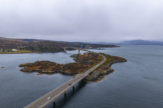 Aerial view of Skye Bridge spanning the sea and connecting the mainland to the island under a cloudy sky Isle of Skye Scotland United Kingdom.