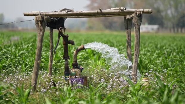 View of a water pump gushing water in a green field Nepal. View of a water pump gushing water in a green field Nepal.