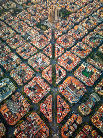 Aerial view of Sagrada Familia surrounded by the dense grid of historic city blocks and terracotta rooftops in the Eixample district Barcelona Catalonia Spain. Aerial view of Sagrada Familia surrounded by the dense grid of historic city blocks and terracotta rooftops in the Eixample district Barcelona Catalonia Spain.