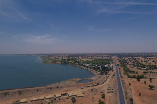 Aerial view of Minjibir Dam featuring the blue water reservoir a long straight road and sparse vegetation in the arid landscape Kano Kano State Nigeria. Aerial view of Minjibir Dam featuring the blue water reservoir a long straight road and sparse vegetation in the arid landscape Kano Kano State Nigeria.