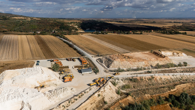Aerial view of the limestone quarry with heavy machinery piles of white earth and surrounding agricultural fields in Besenovo Vojvodina Serbia. Aerial view of the limestone quarry with heavy machinery piles of white earth and surrounding agricultural fields in Besenovo Vojvodina Serbia.