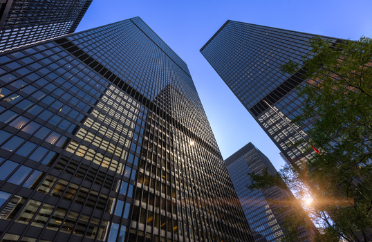 View of modern black skyscrapers in the financial district with glass facades reflecting the clear blue sky and green trees in the foreground Toronto Ontario Canada. View of modern black skyscrapers in the financial district with glass facades reflecting the clear blue sky and green trees in the foreground Toronto Ontario Canada.