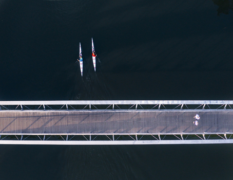 Aerial view of Tel Aviv Port showing a pedestrian bridge over dark water with two kayaks and people walking on the wooden deck in Tel Aviv Yafo Tel Aviv District Israel. Aerial view of Tel Aviv Port showing a pedestrian bridge over dark water with two kayaks and people walking on the wooden deck in Tel Aviv Yafo Tel Aviv District Israel.