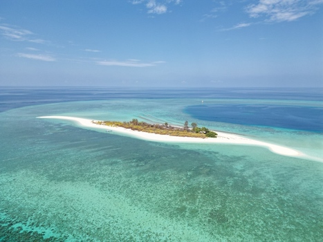 Aerial view of Pulau Ndaa with its pristine white sand beach surrounded by vibrant turquoise coral reefs and deep blue ocean waters in Tomia South East Sulawesi Indonesia.
