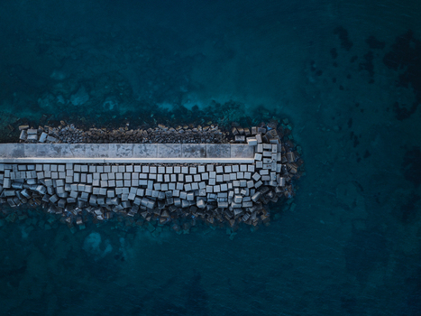 Aerial view of a concrete breakwater and protective stone blocks surrounded by deep blue sea water at the Island of Ortigia Syracuse Sicily Italy. Aerial view of a concrete breakwater and protective stone blocks surrounded by deep blue sea water at the Island of Ortigia Syracuse Sicily Italy.