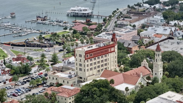 Aerial view of the historic Cathedral Basilica of St. Augustine and the Lightner Museum surrounded by lush trees rooftops and the nearby marina in St. Augustine Florida United States. Aerial view of the historic Cathedral Basilica of St. Augustine and the Lightner Museum surrounded by lush trees rooftops and the nearby marina in St. Augustine Florida United States.