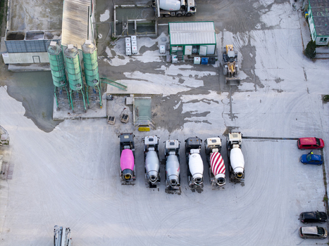 Aerial view of a concrete batching plant featuring several cement mixer trucks parked in a row industrial silos and construction equipment in Krakow Lesser Poland Voivode Poland. Aerial view of a concrete batching plant featuring several cement mixer trucks parked in a row industrial silos and construction equipment in Krakow Lesser Poland Voivode Poland.