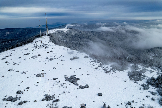 Aerial view of the snowy peak of Hornisgrinde with a communications tower and wind turbine surrounded by winter forest in the Black Forest Seebach Baden Wurttemberg Germany. Aerial view of the snowy peak of Hornisgrinde with a communications tower and wind turbine surrounded by winter forest in the Black Forest Seebach Baden Wurttemberg Germany.