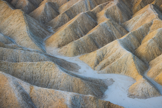 View of the eroded badlands and ridges of Death Valley National Park at golden hour in the United States.