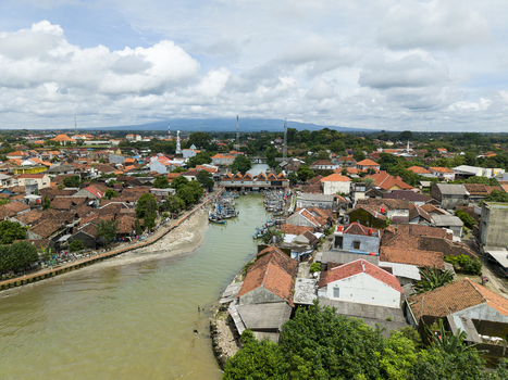 Aerial view of a vibrant town where the river meets the sea its terracotta rooftops contrasting with the lush greenery Jepara Central Java Indonesia.