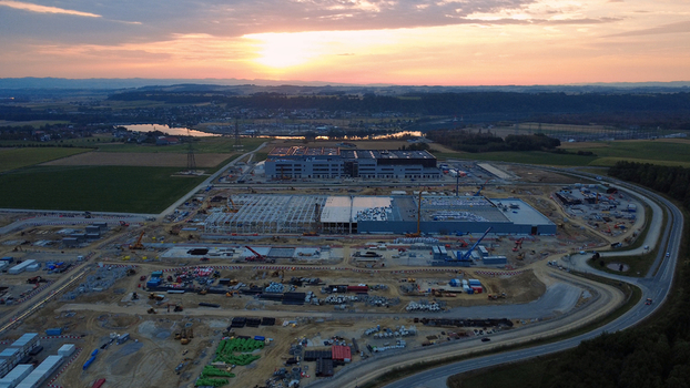 Aerial view of a large data center construction site with cranes and industrial buildings under a golden sunrise in the rural landscape of Kronstorf Upper Austria Austria.