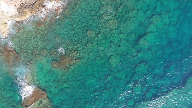 Aerial view of turquoise coastal waters and rocky shore Cyprus.