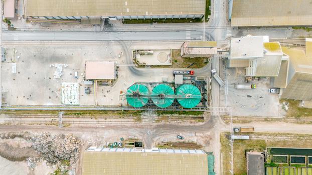 Aerial view of an industrial facility featuring three large green silos warehouses and trucks parked near loading docks in Sabac Vojvodina Serbia. Aerial view of an industrial facility featuring three large green silos warehouses and trucks parked near loading docks in Sabac Vojvodina Serbia.
