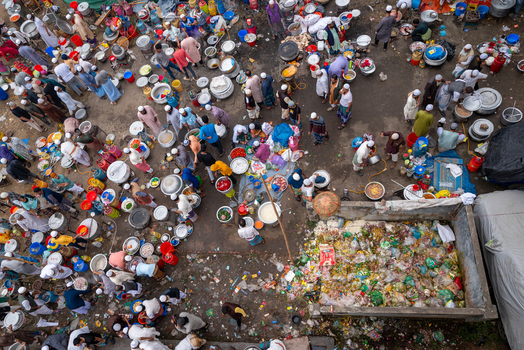 Tongi Bangladesh 31 January 2025 Aerial view of the Tongi Ijtema Maidan with numerous people cooking meals in large pots surrounded by scattered food waste and cooking equipment.