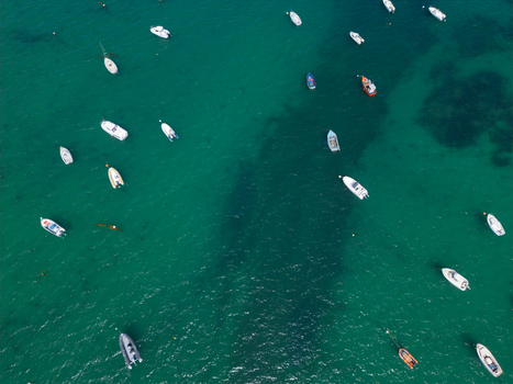 Aerial view of small motorboats and dinghies anchored in the clear turquoise waters of Plage de Port Blanc Penvenan Bretagne France. Aerial view of small motorboats and dinghies anchored in the clear turquoise waters of Plage de Port Blanc Penvenan Bretagne France.