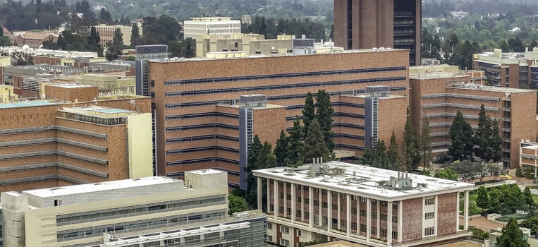 Aerial view of the UCLA Campus featuring red brick academic buildings lush green trees and modern architectural structures in Westwood California United States.