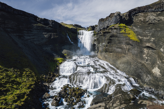 Aerial view of Ofaerufoss falls cascading down the dark cliffs a contrast to the bright water with green moss clinging to the rocks Highlands of Iceland. Aerial view of Ofaerufoss falls cascading down the dark cliffs a contrast to the bright water with green moss clinging to the rocks Highlands of Iceland.