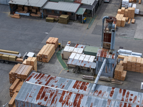 Melbourne VIC Australia 25 September 2026 Aerial view of a timber processing facility with stacks of lumber industrial machinery and corrugated metal rooftops.