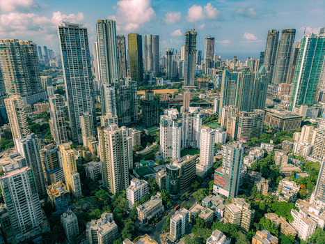 Aerial view of the dense urban skyline featuring numerous modern skyscrapers and high rise residential towers under a clear sky with soft clouds in Mumbai Maharashtra India. Aerial view of the dense urban skyline featuring numerous modern skyscrapers and high rise residential towers under a clear sky with soft clouds in Mumbai Maharashtra India.