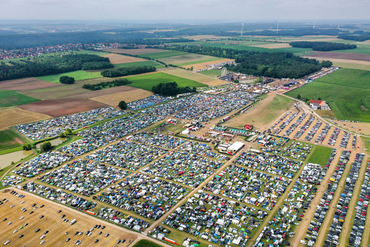 Herzogenaurach Germany 26 July 2025 Aerial view of Open Beatz Festival with vast camping grounds parking areas and stages surrounded by green fields and forests.