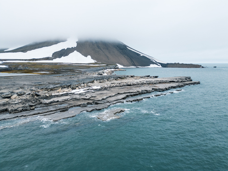 Svalbard and Jan Mayen 28 July 2025 Aerial view of the rugged rocky coastline and snow capped mountain partially hidden by low clouds. Svalbard and Jan Mayen 28 July 2025 Aerial view of the rugged rocky coastline and snow capped mountain partially hidden by low clouds.