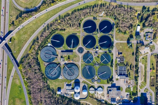 Aerial view of circular wastewater treatment pools contrasting with the linear highway and surrounding lush greenery Sausheim Grand Est France.