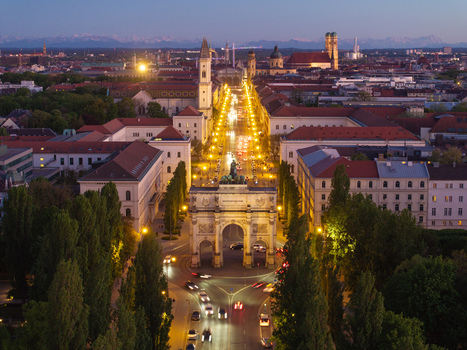 Aerial view of the Siegestor victory arch and illuminated Ludwigstrasse at twilight with the Alps on the horizon in Munich Bavaria Germany. Aerial view of the Siegestor victory arch and illuminated Ludwigstrasse at twilight with the Alps on the horizon in Munich Bavaria Germany.
