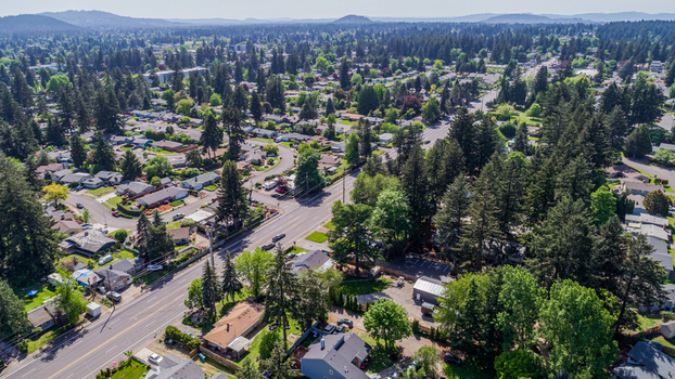 Aerial view of Northeast Glisan Street passing through a residential neighborhood with dense evergreen trees and suburban houses in Portland Oregon United States. Aerial view of Northeast Glisan Street passing through a residential neighborhood with dense evergreen trees and suburban houses in Portland Oregon United States.