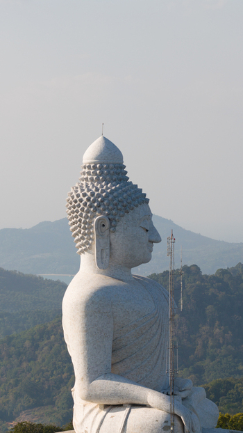 Aerial view of the Big Buddha Phuket statue in profile overlooking lush green hills and the Andaman Sea Karon Phuket Thailand. Aerial view of the Big Buddha Phuket statue in profile overlooking lush green hills and the Andaman Sea Karon Phuket Thailand.