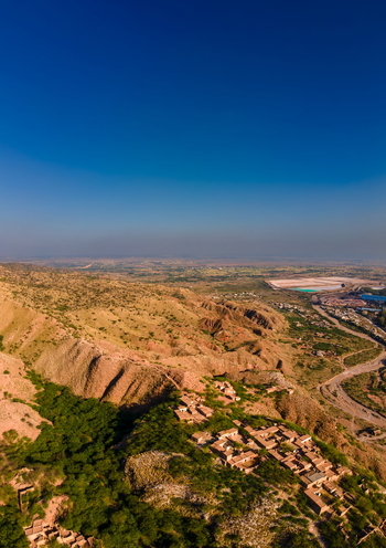 Aerial view of the rugged landscape surrounding the Khewra Salt Mine with a small village nestled among the hills under a clear blue sky in Khewra Punjab Pakistan.