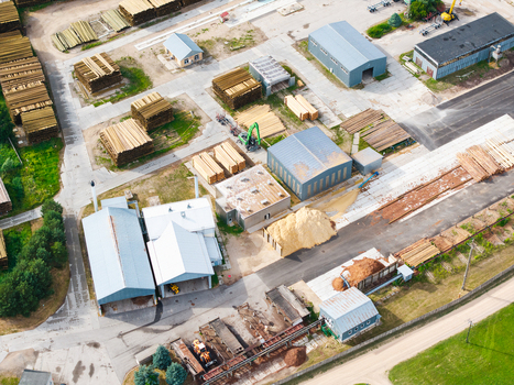 Aerial view of a timber processing facility with stacks of lumber industrial buildings and piles of wood chips in Latvia. Aerial view of a timber processing facility with stacks of lumber industrial buildings and piles of wood chips in Latvia.